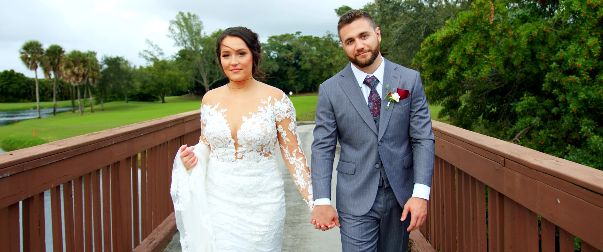A newlywed couple walking together on a garden bridge.